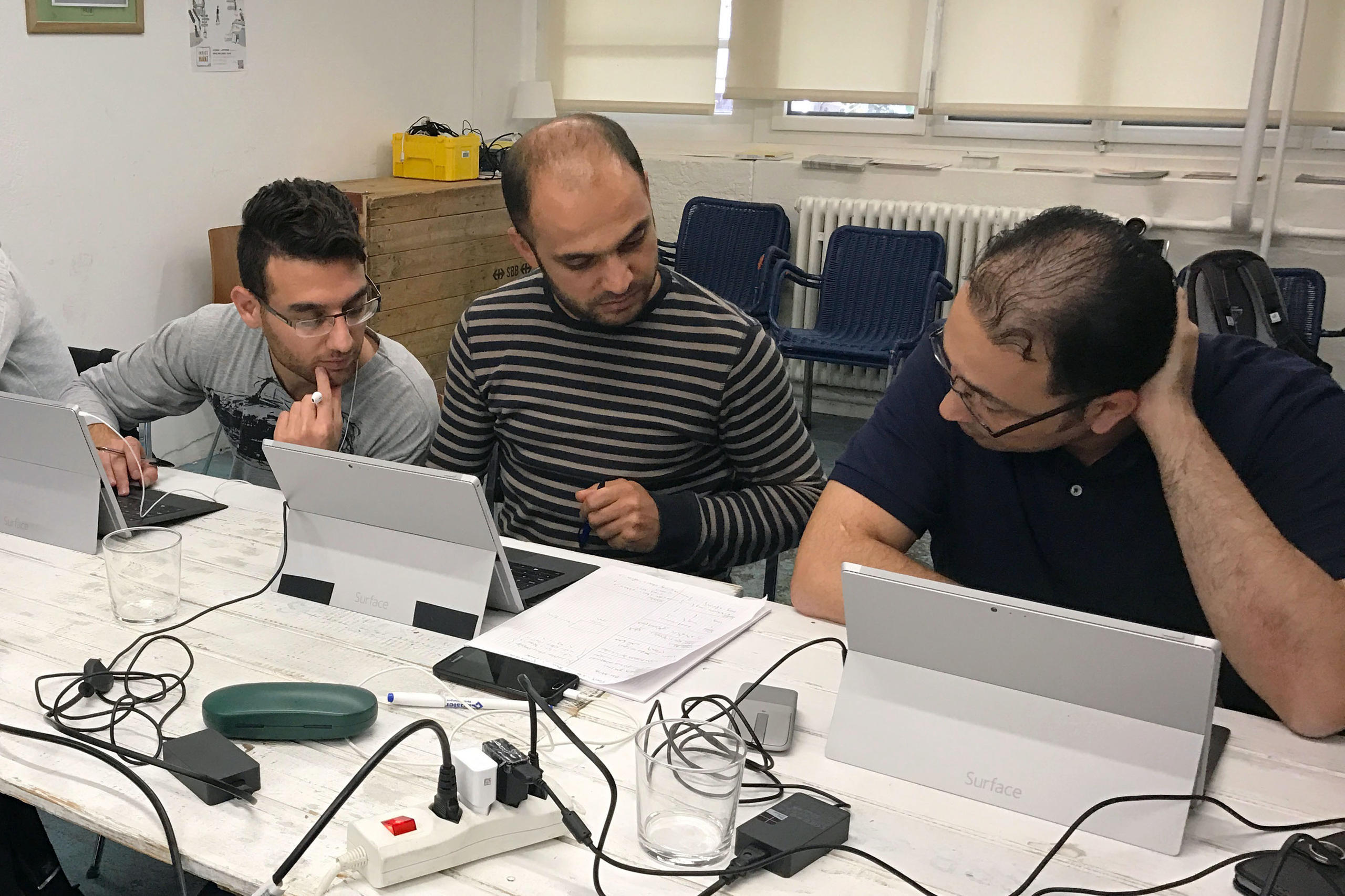 Three men working at the computer.