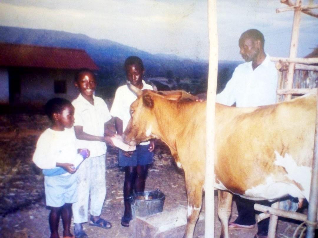 Ashery Mbilinyi fotografado na Tanzânia em 1995 com seus dois irmão, pai e a vaca da família