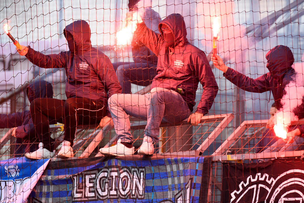 Masked football fans wave flares at a match in Lausanne