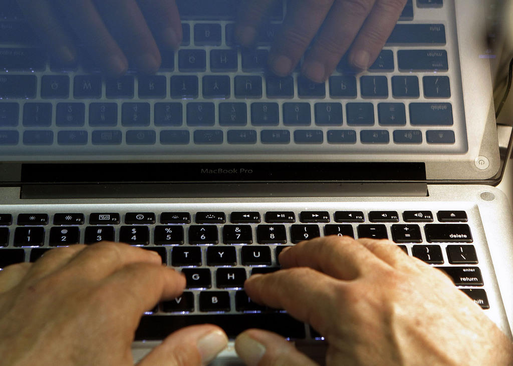 Hands type on a computer keyboard