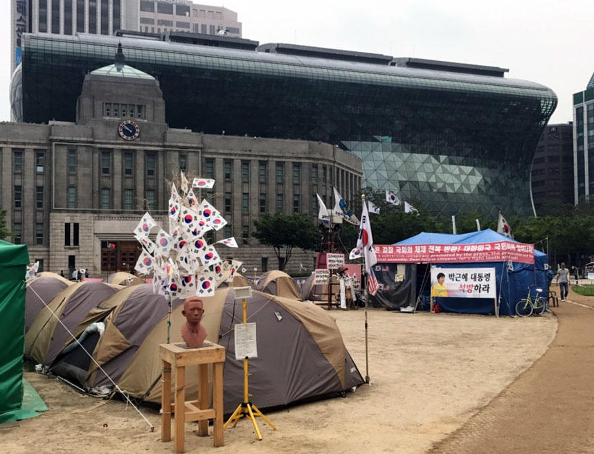 Seoul s new Citizen Hall and the old City Hall in the background, a protest camp on Democracy Plaza