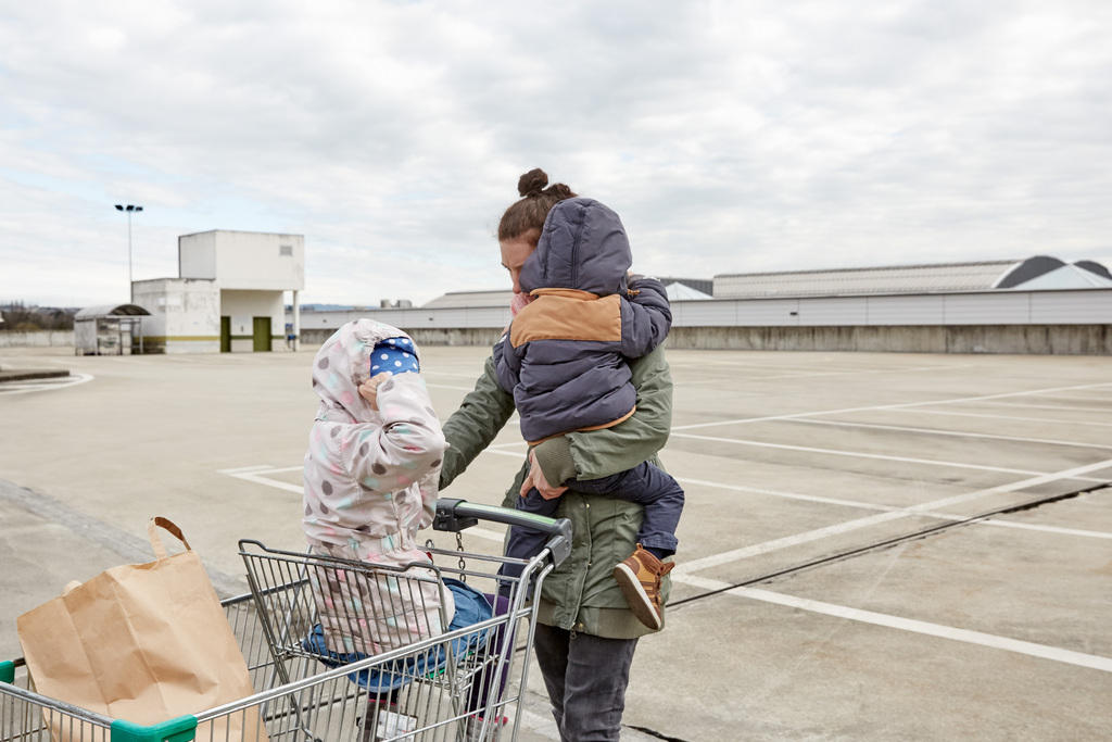 Una madre con dos hijos sale del supermercado.