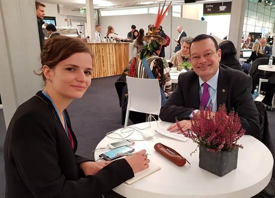 Eine Frau macht mit einem Mann an einem Tisch sitzend ein Interview.