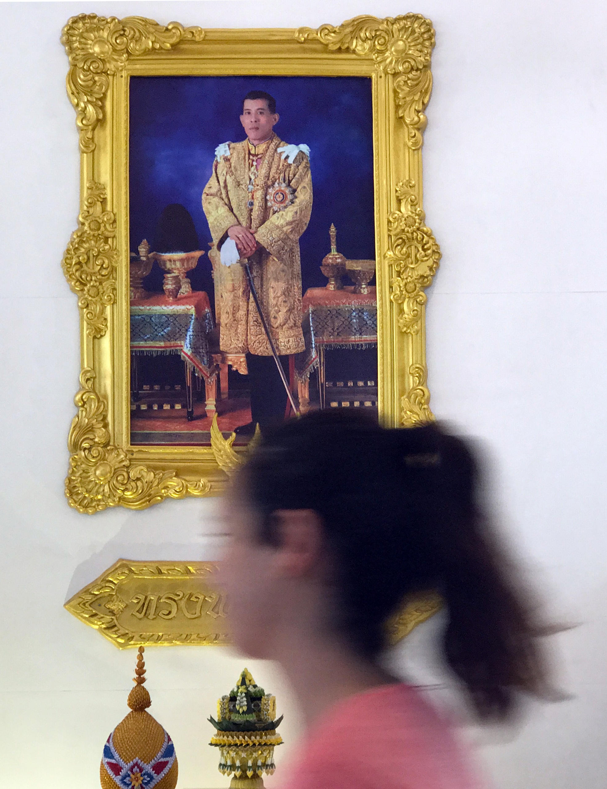 Woman walking past a portrait of King of Thailand Maha Vajiralongkorn