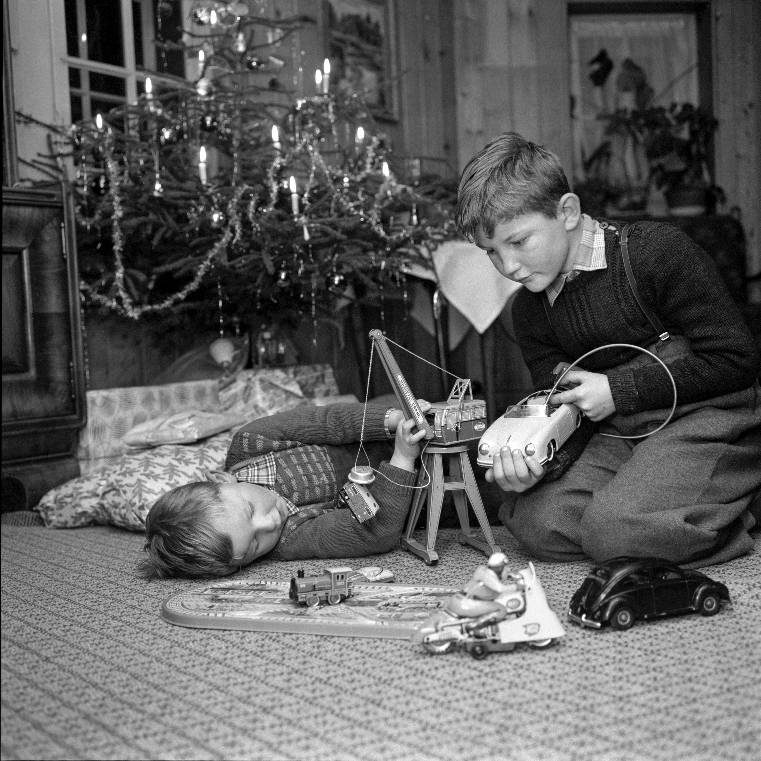Two boys with their presents in front of a Christmas tree.
