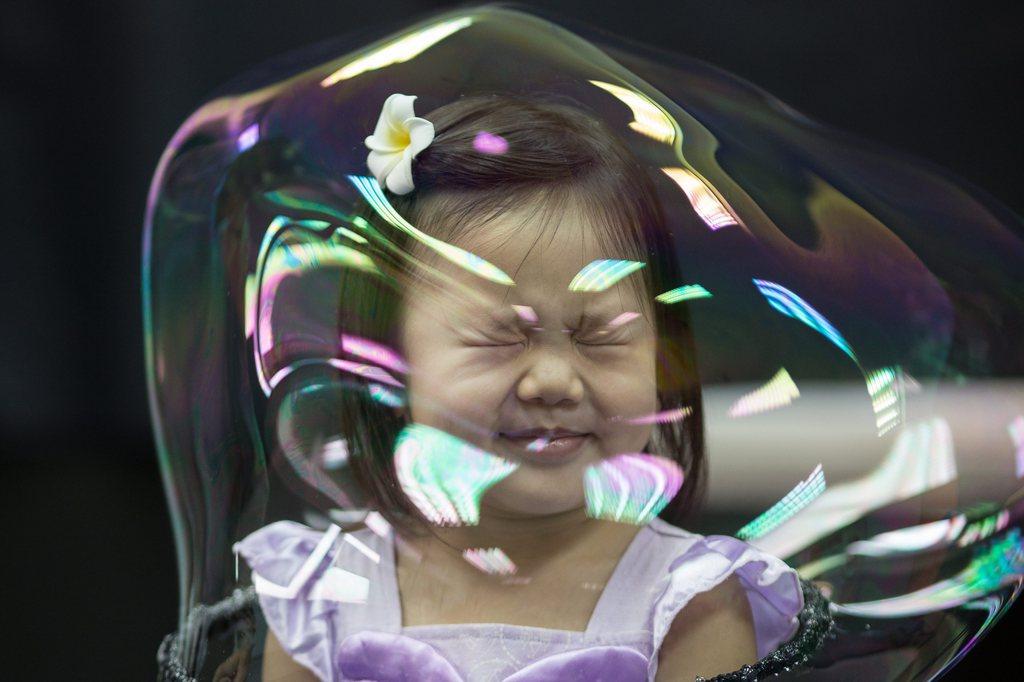 A girl grimaces with her head in a bubble