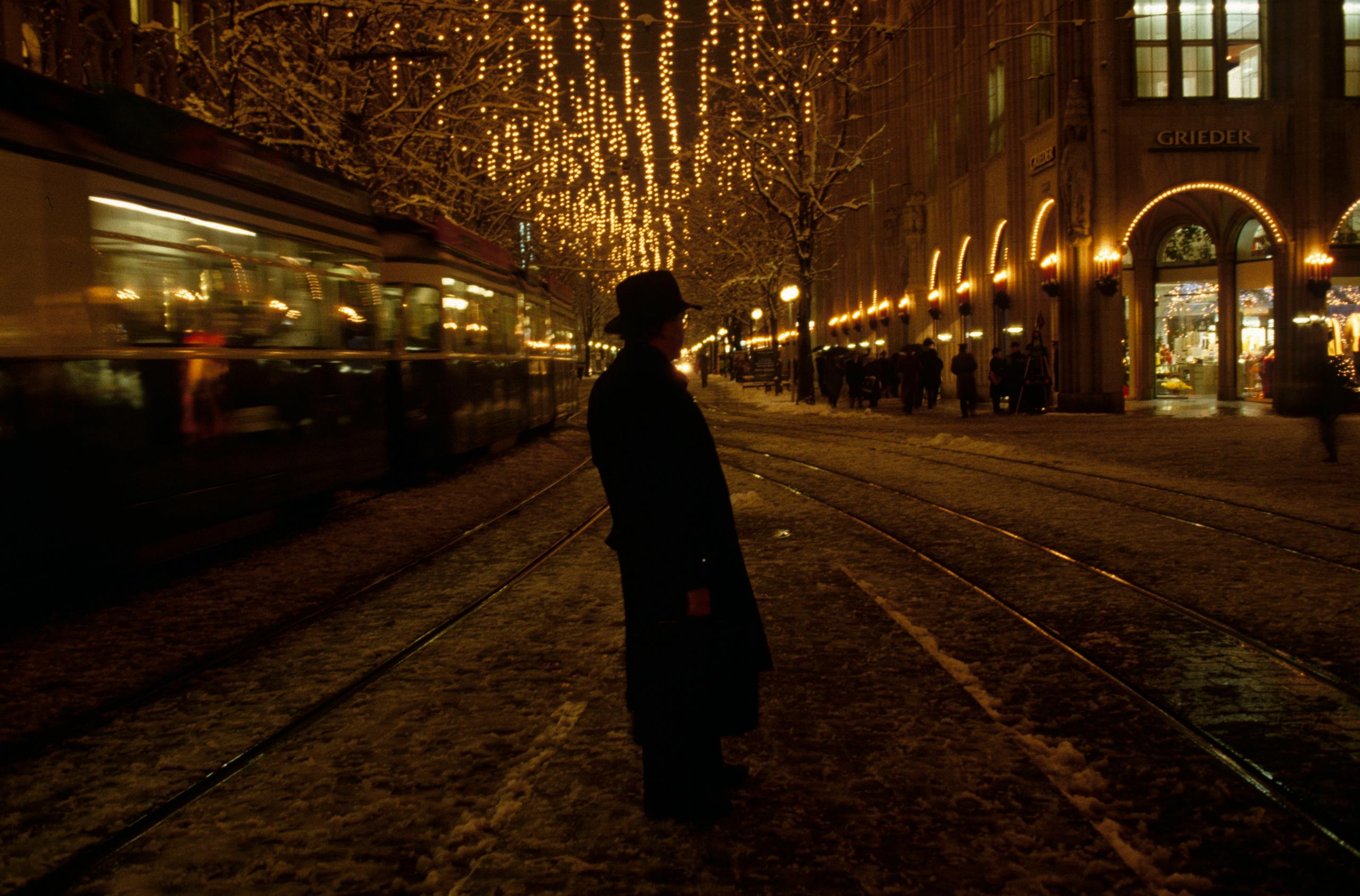 uomo in mezzo alla strada in una notte illuminata dalle luci natalizie