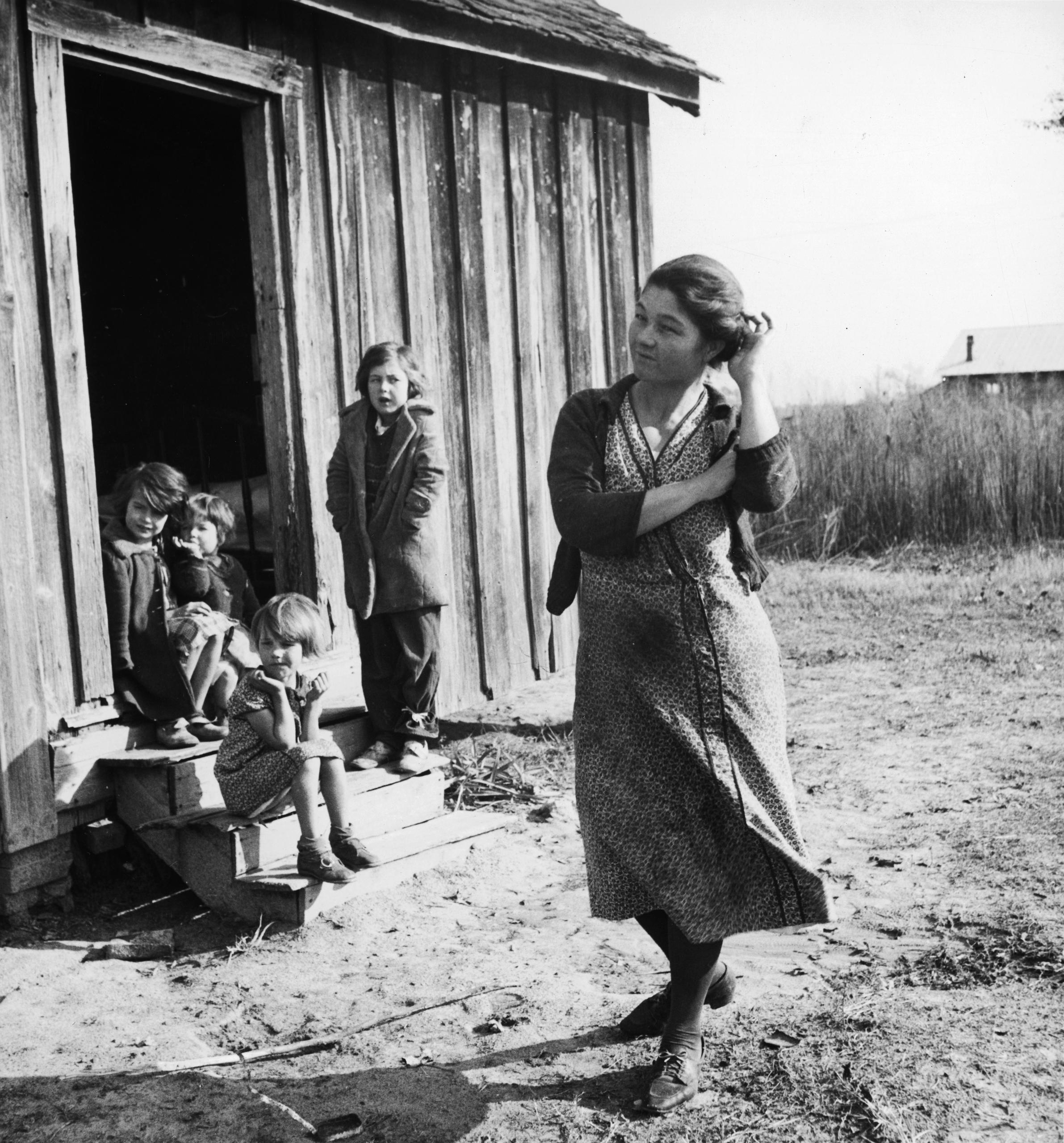Femme avec quatre enfants devant une maison