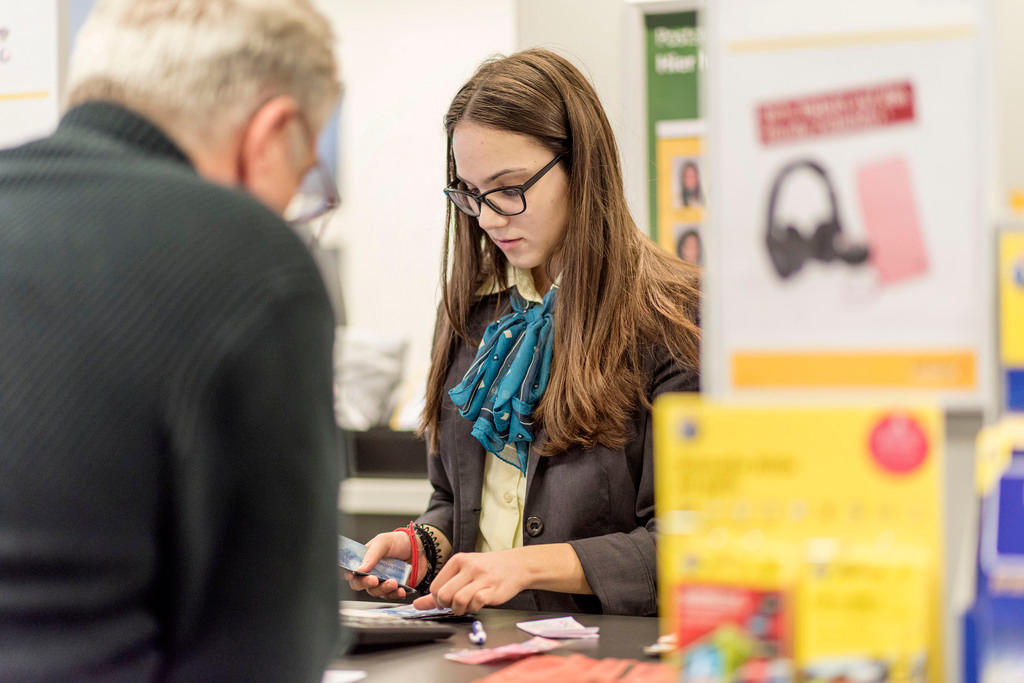 young woman serves man in post office