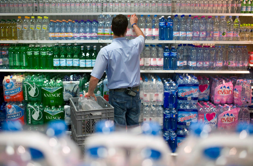 An employee stocks bottled beverages in a Swiss supermarket