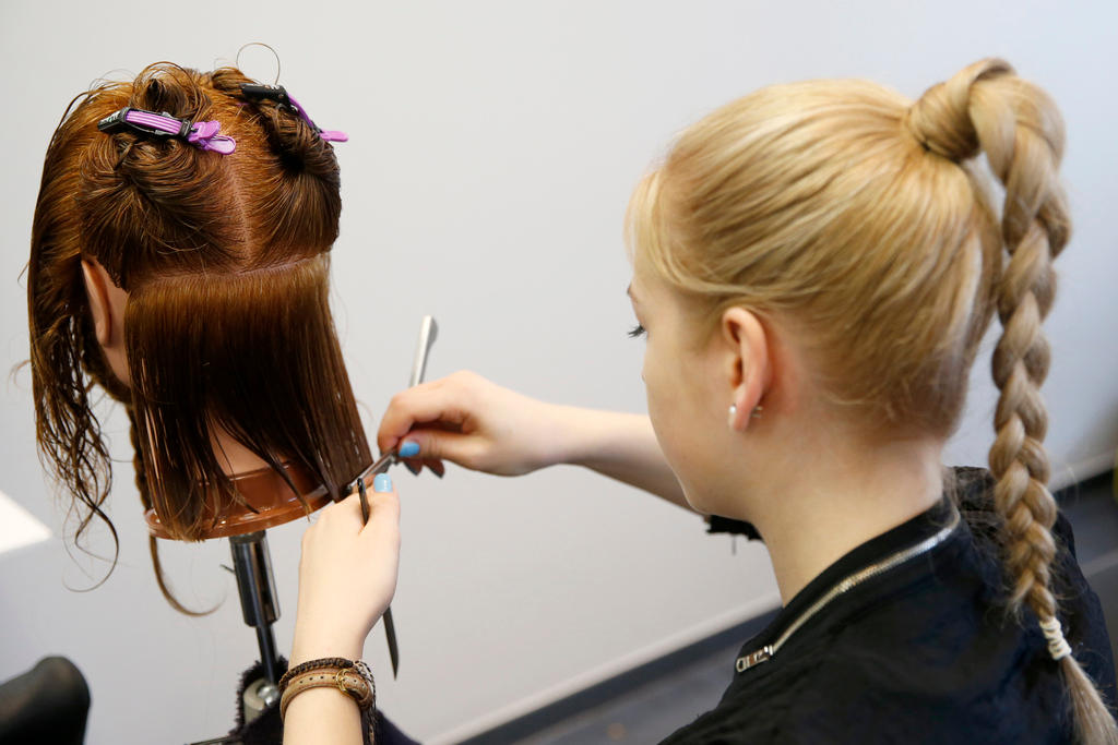 An apprentice practices styling hair