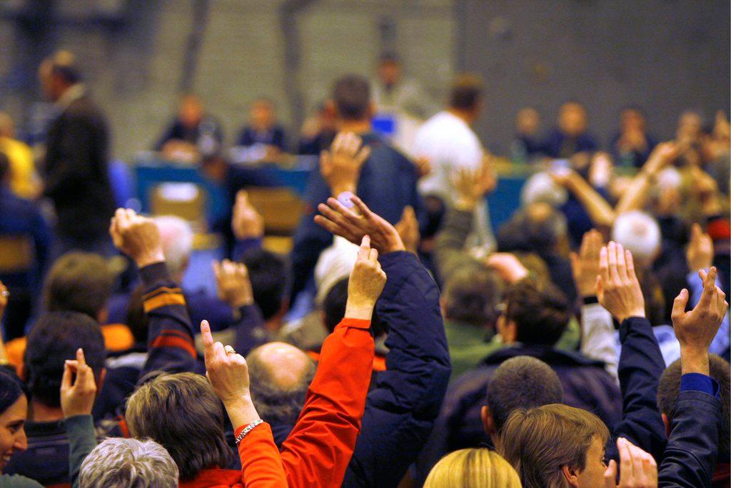 gente alza la mano per votare