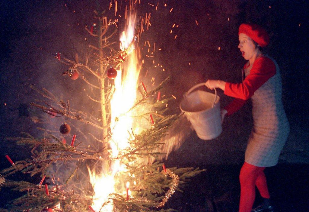 A woman douses a burning Christmas tree