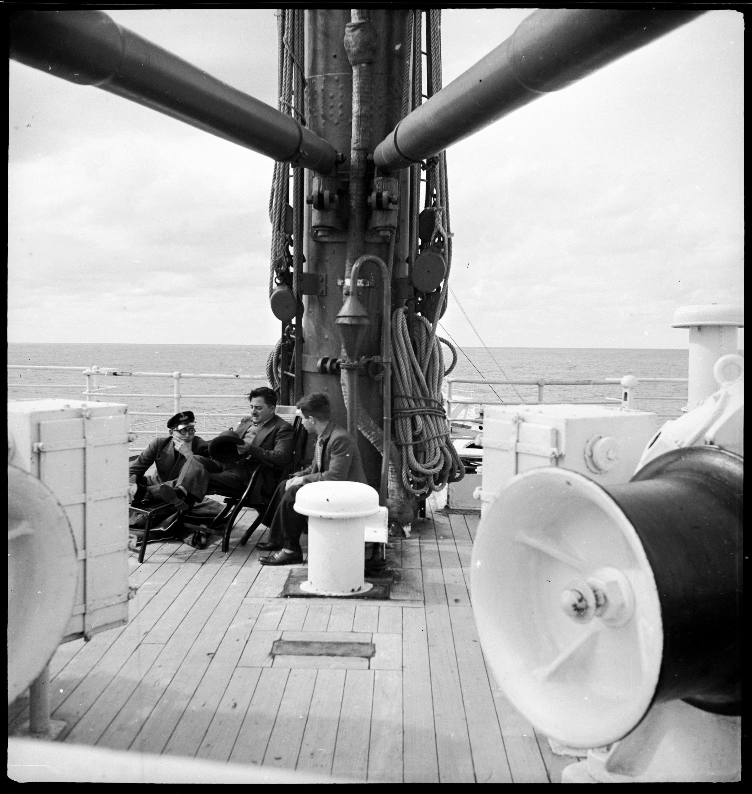 трое мужчин сидят на скамейке на палубе корабля