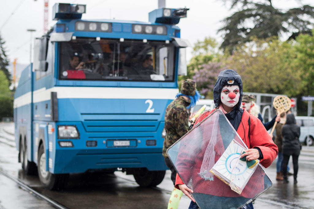 Clownin vor einem Wasserwerfer der Polizei