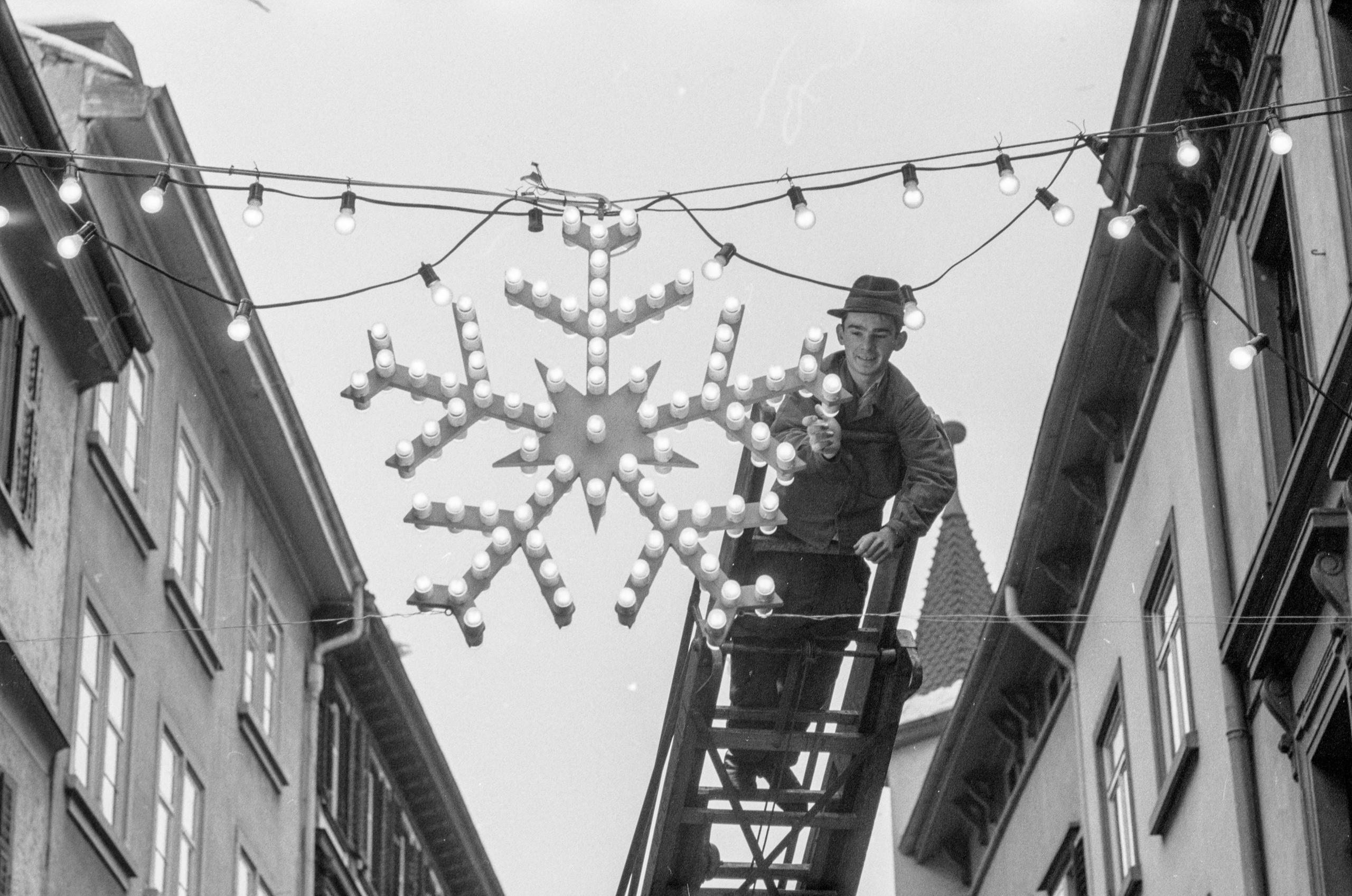 un operaiop su una scala sta aggiungendo una lampadina a una decorazione natalizia