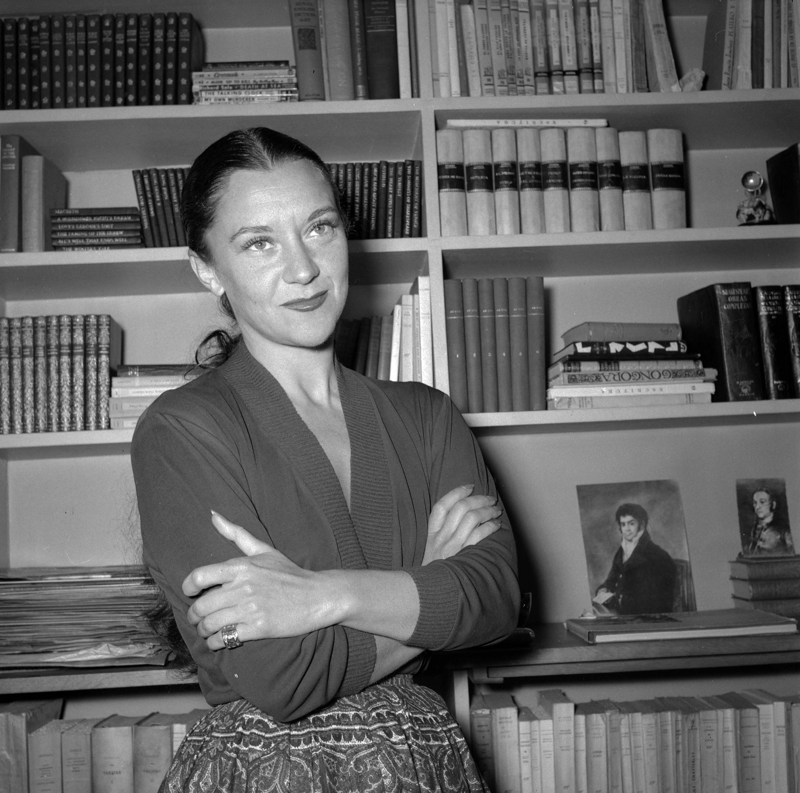 Foto en blanco y negro de María Casares delante de una estantería de libros