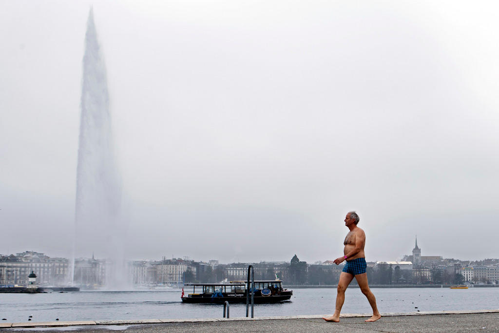 A winter bather walks in front of the famous water fountain Le Jet d Eau