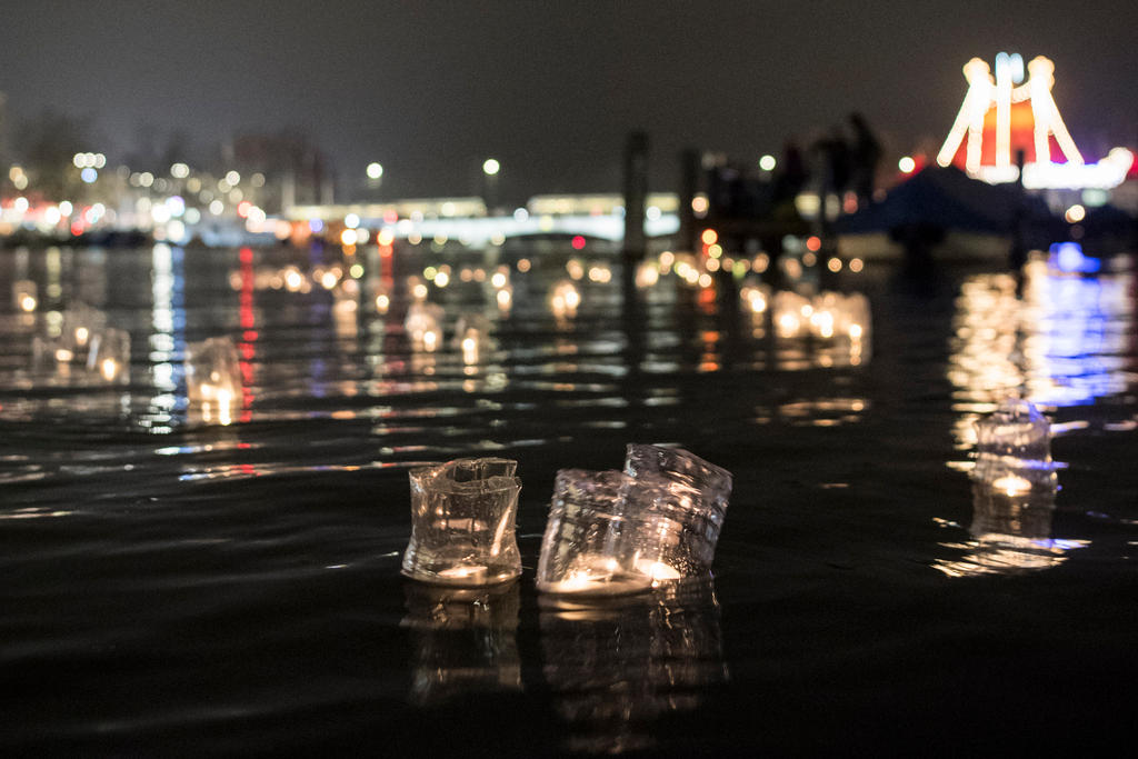 Kerzen in abgeschnittenen Petflaschen auf dem Fluss treibend