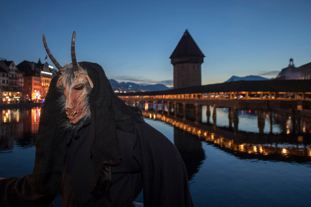 Person mit einer Fasnachtsmaske vor der Kapellbrücke in Luzern