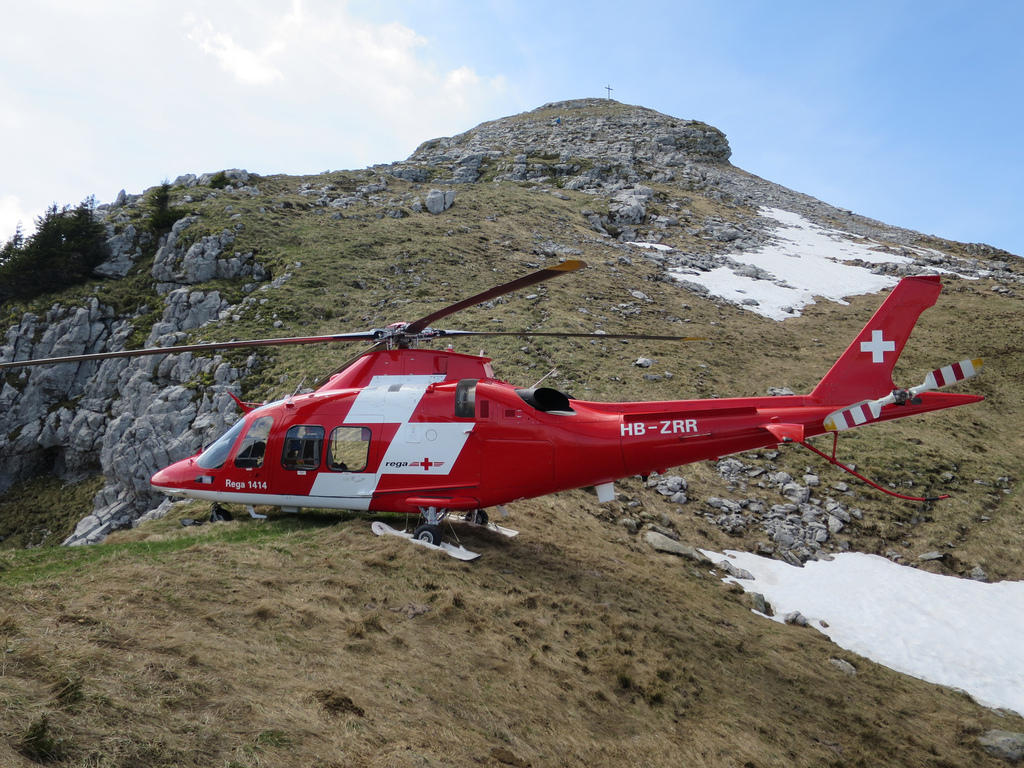 A red Rega rescue helicopter on a mountain top