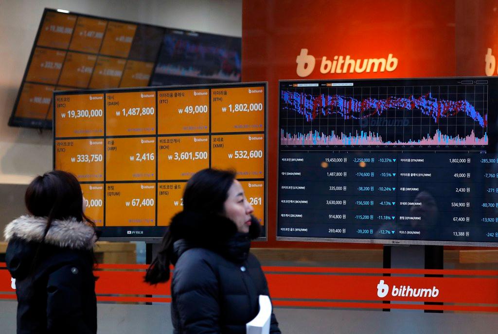 ビットコインの相場を示すボードに見入る通行人