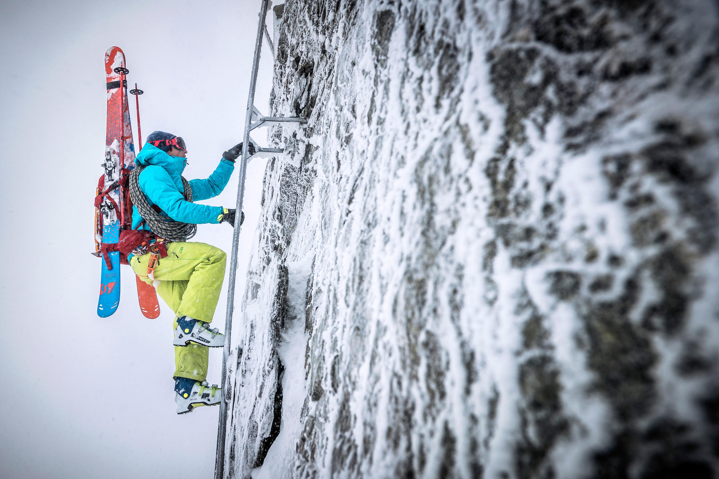 skier climbing a ladder on a snowy rock face