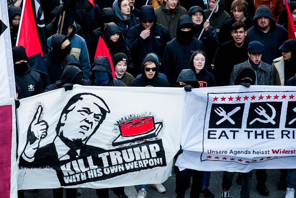 Manifestantes com uma faixa escrito Mate Trump com sua própria arma