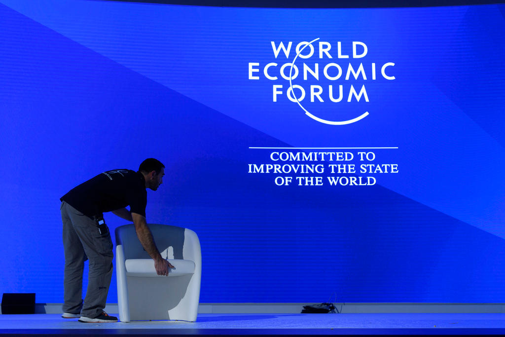 Homem arrumando uma poltrona no palco do WEF
