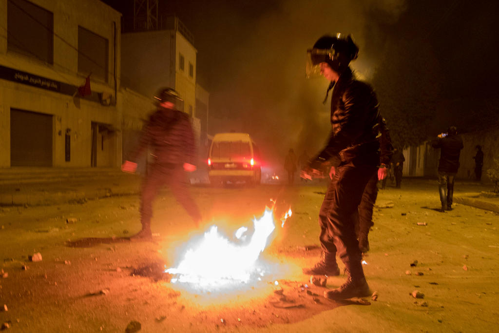 poliziotti in assetto antisommossa tentano di spegnere un focolare d incendio