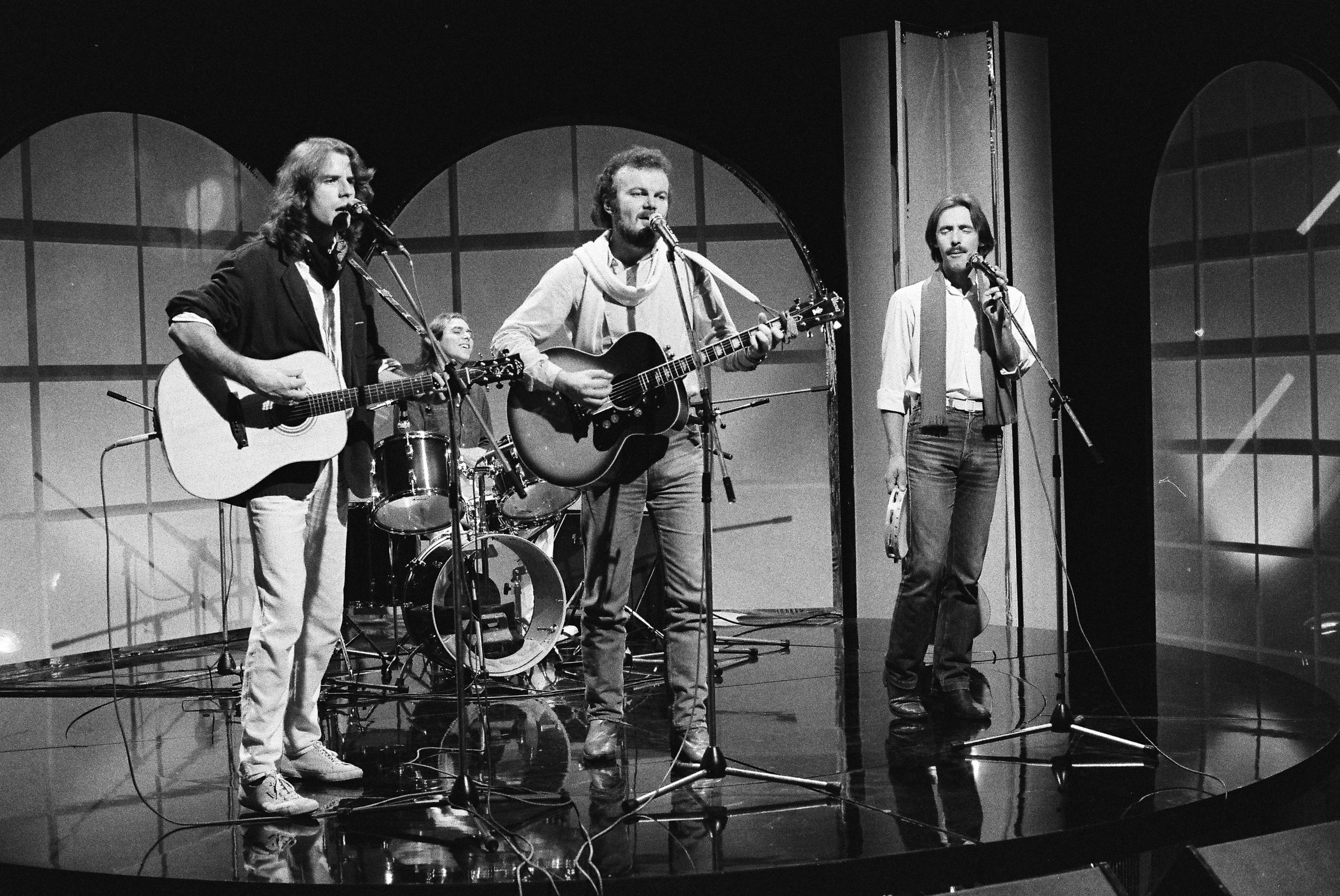 Marco Ferradini al microfono, e Mario Castelnuovo e Goran Kuzminac alla chitarra, su un palcoscenico.