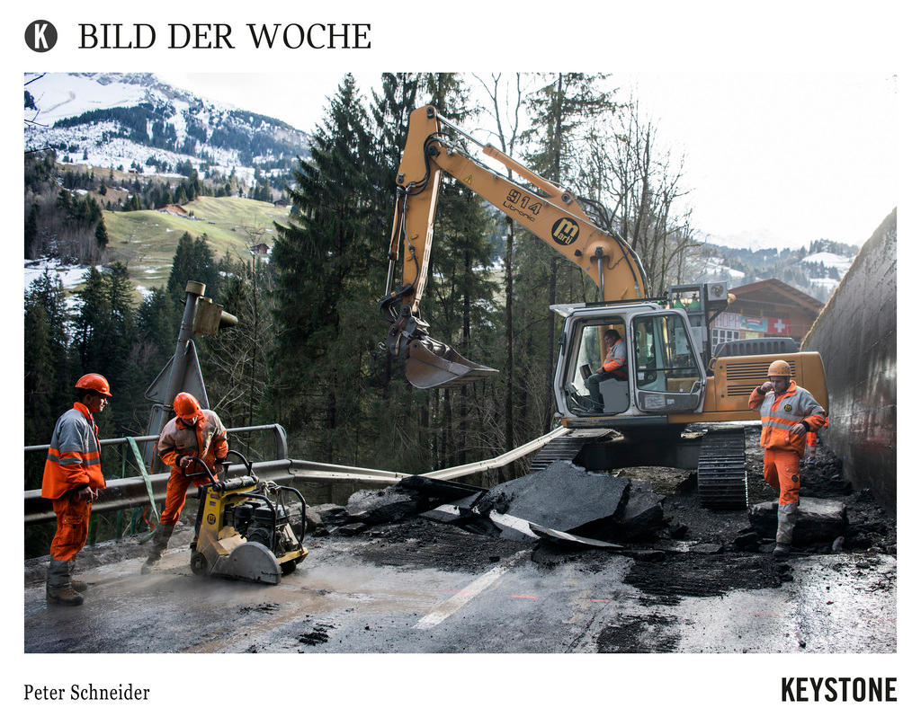 Workers clear the damaged road after a landslide between Frutigen and Adelboden on January 5, 2018