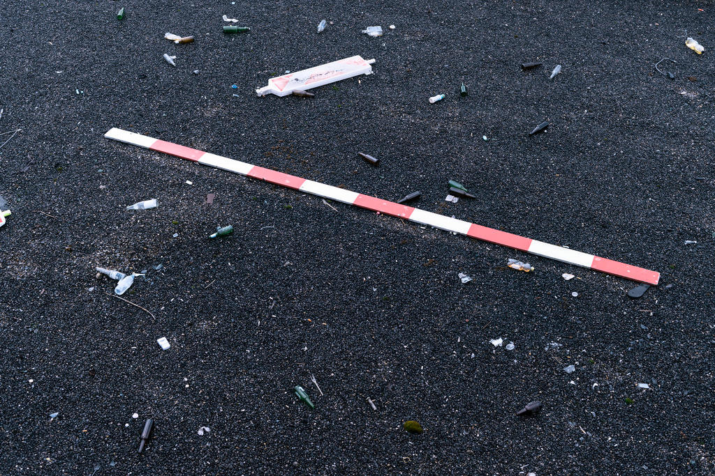 A safety cordon, a delineator and empty bottles on a gravel roof