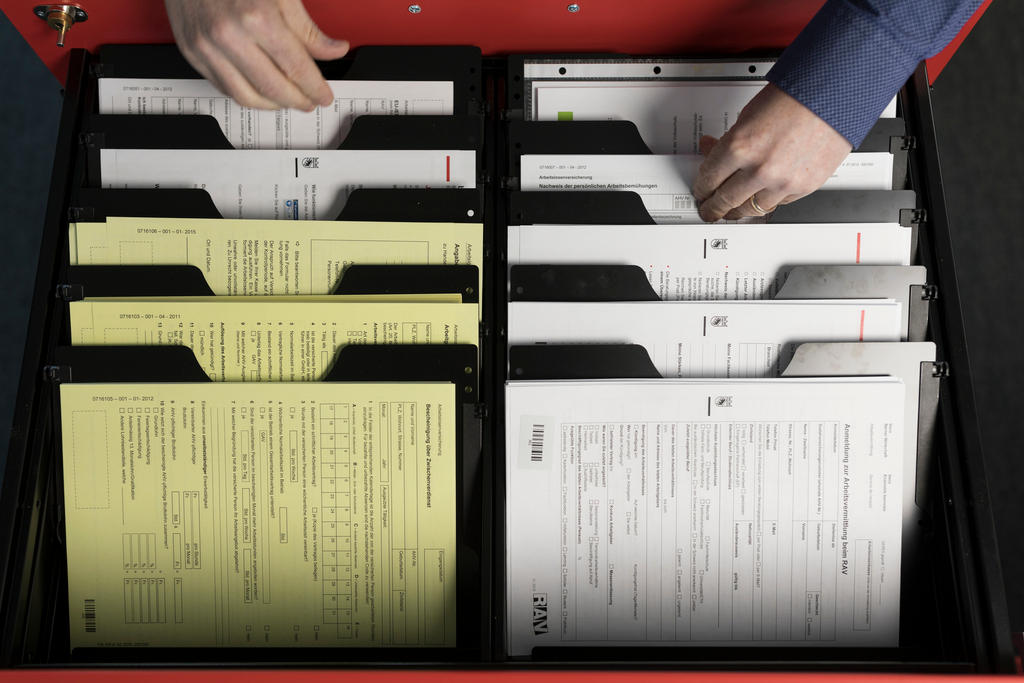 A receptionist takes a document out of a drawer