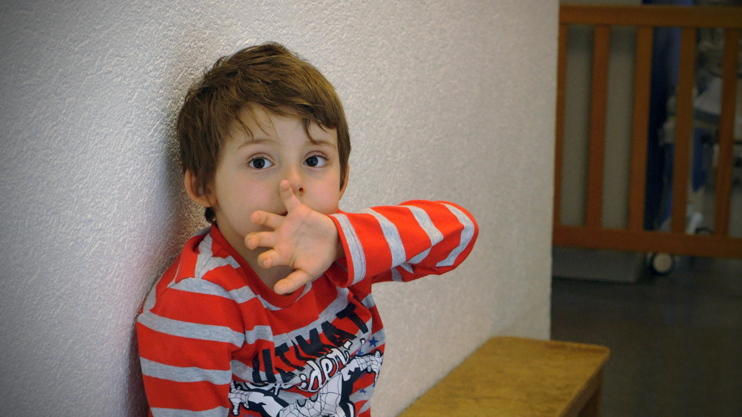 Immagine di un bambino (Louis) seduto su una panca accanto a un muro.