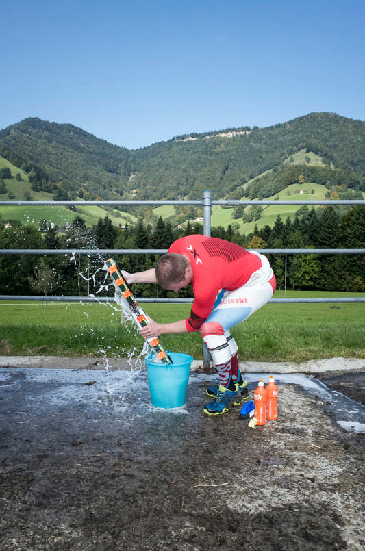 Ein Mann wäscht seinen Grasski mit Wasser