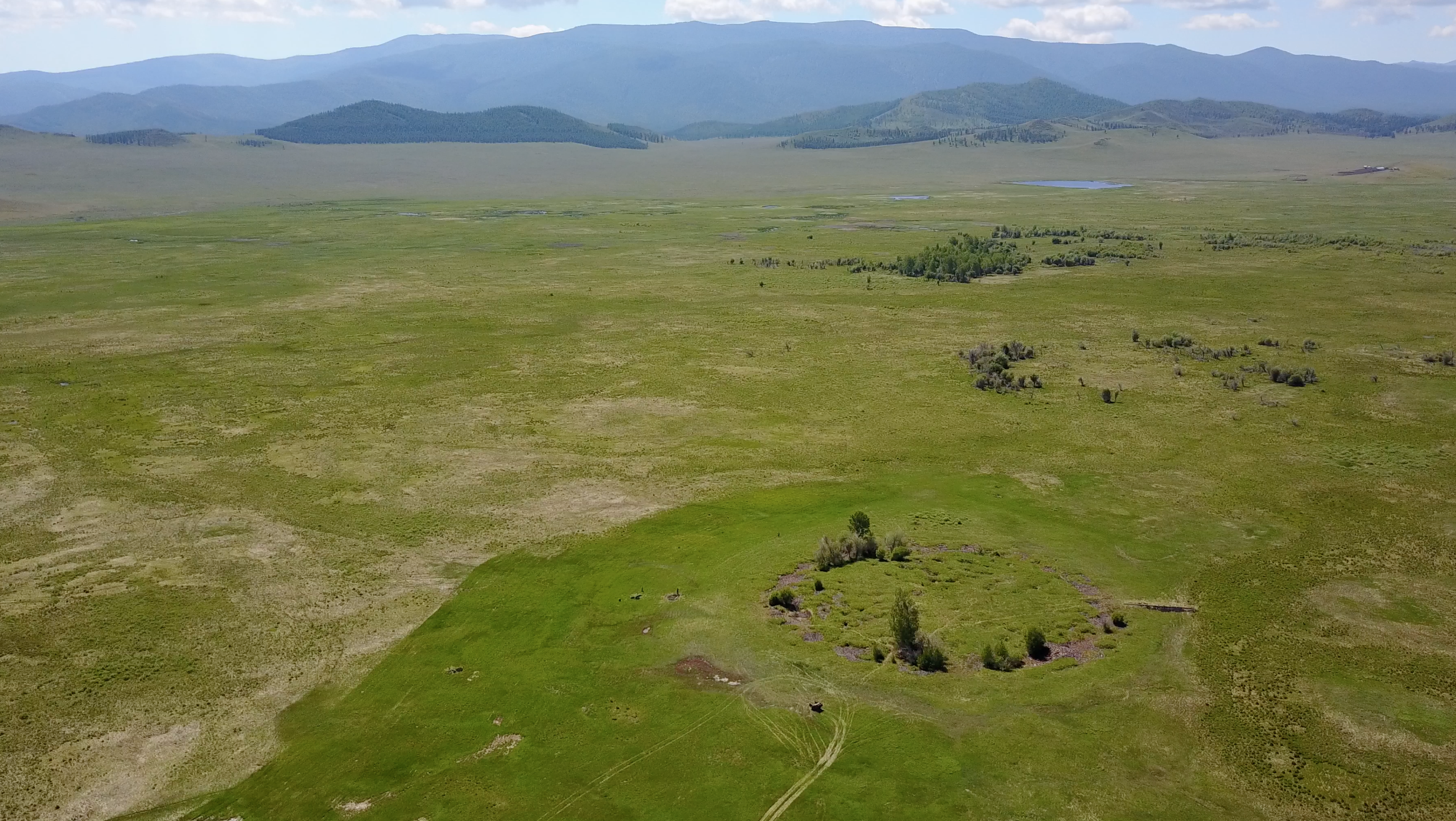 Grassland with mountains in the background and two mounds