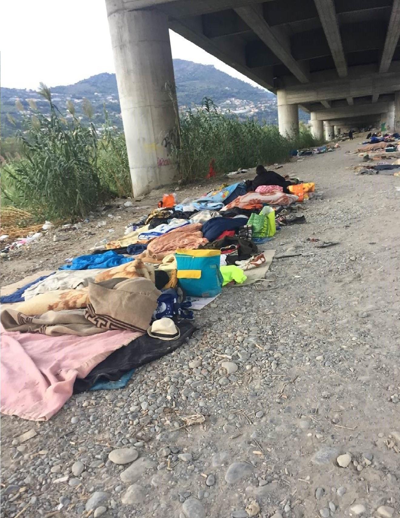 Coperte, teli, cartoni e altri giacigli sotto un viadotto a Ventimiglia.