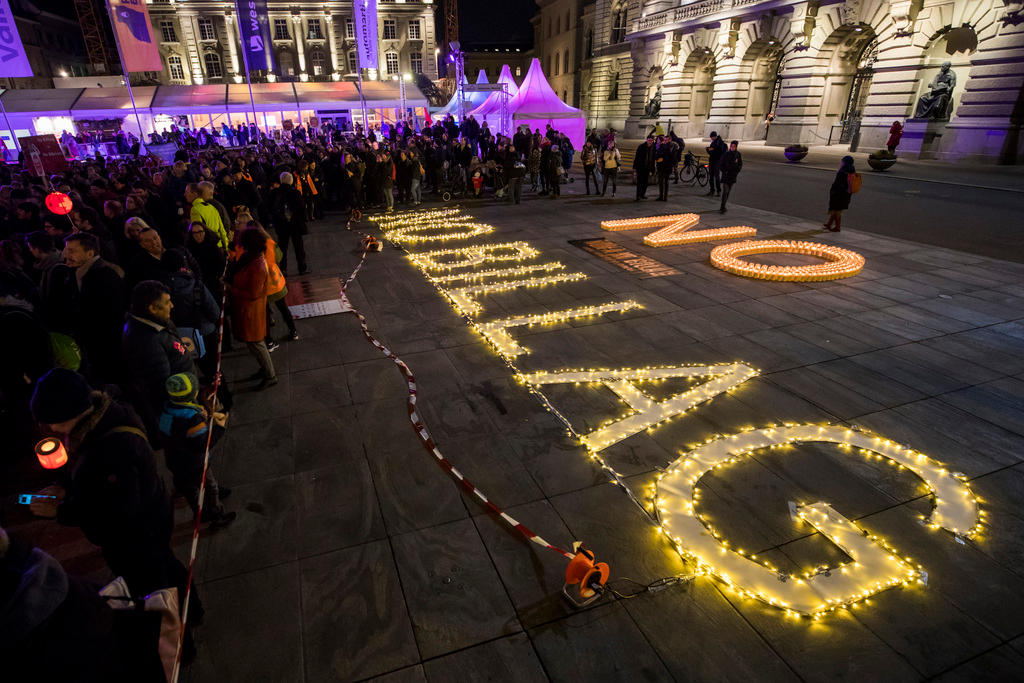 People gather around an illuminated no billag sign