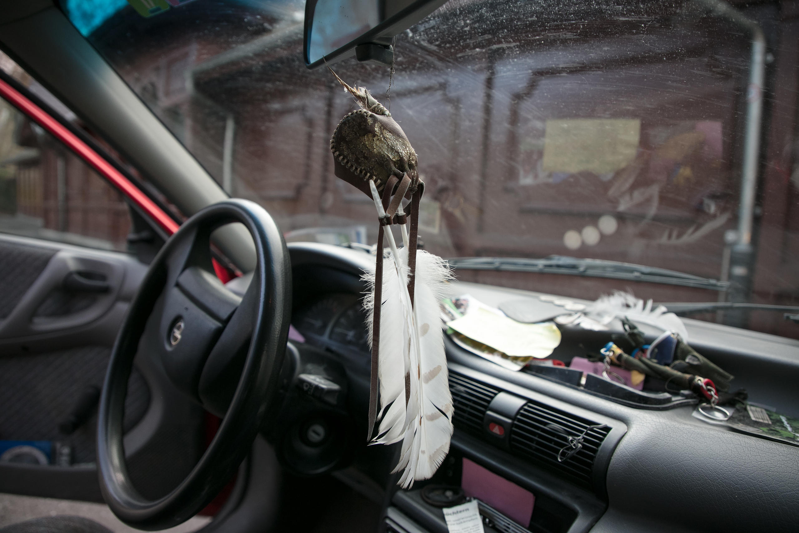 Una caperuza de halcón con plumas de búho cuelga del retrovisor en el auto de Ulrich Lüthi.