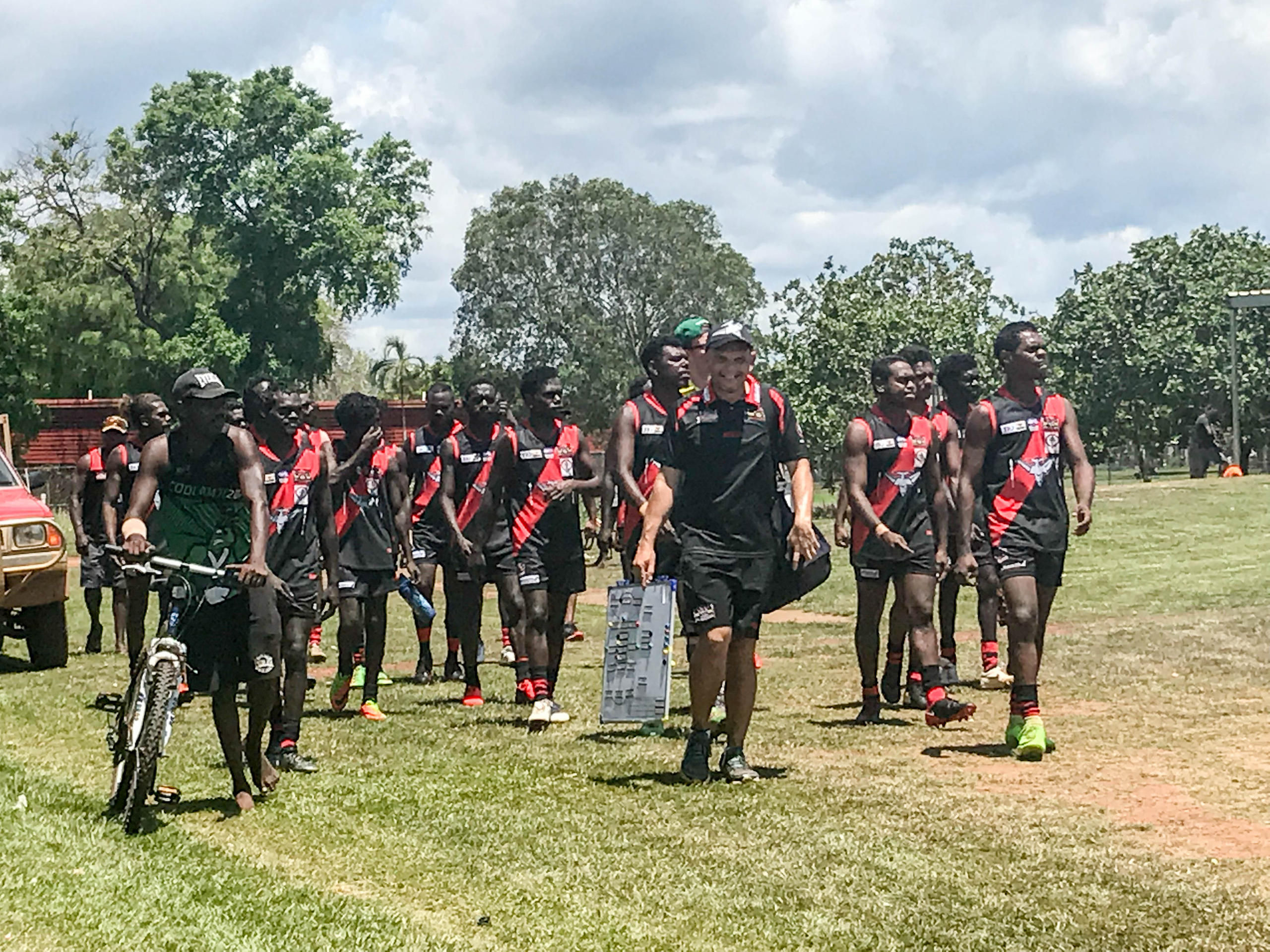 A team of Tiwi footy players entering the playfield