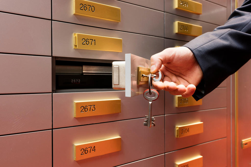 A bank employee uses a key to open a client safety deposit box