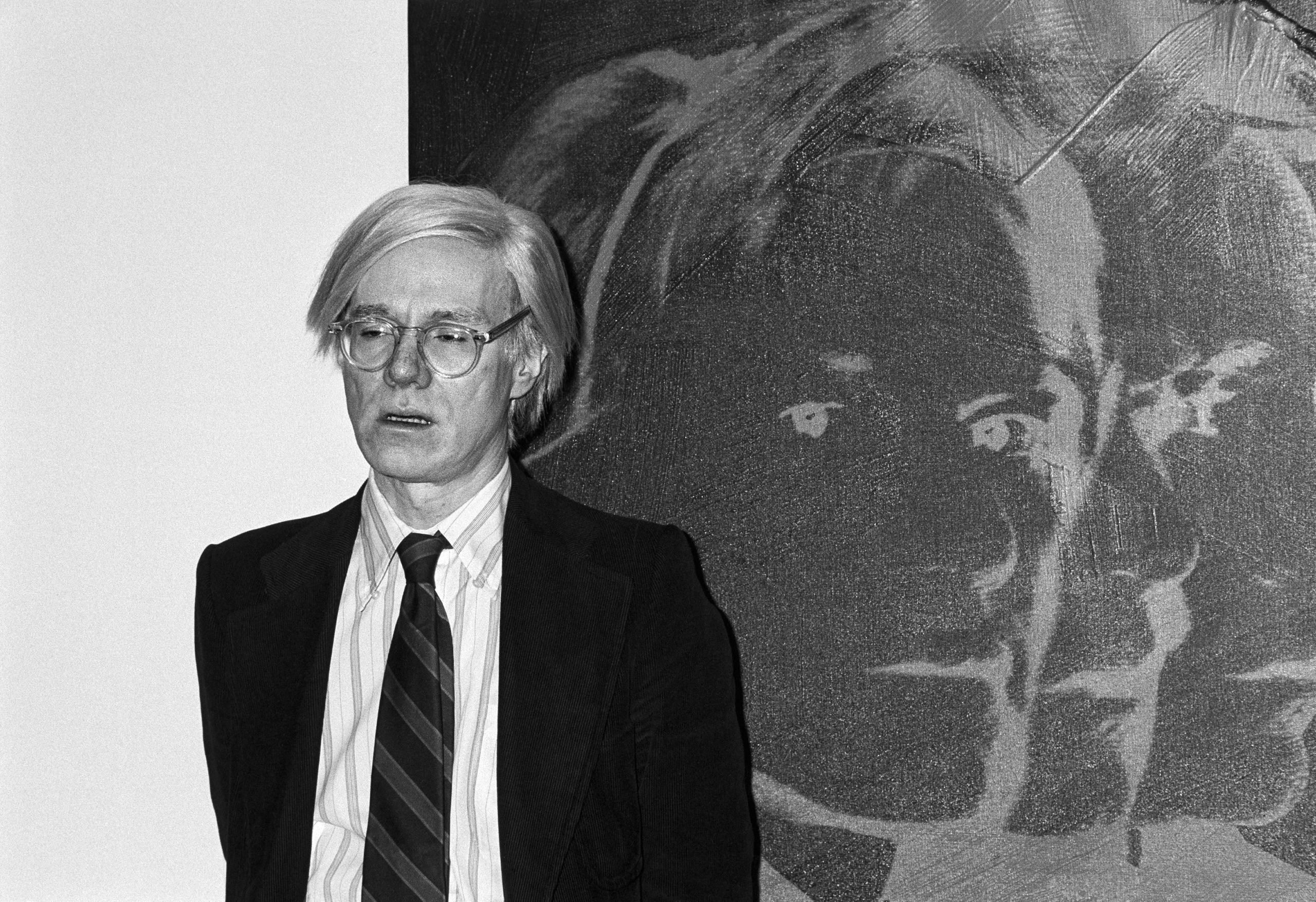 الفنان الأمريكي أندي وارهول يقف أمام عمله بورتريه ذاتي أثناء معرض أقيم في زيورخ