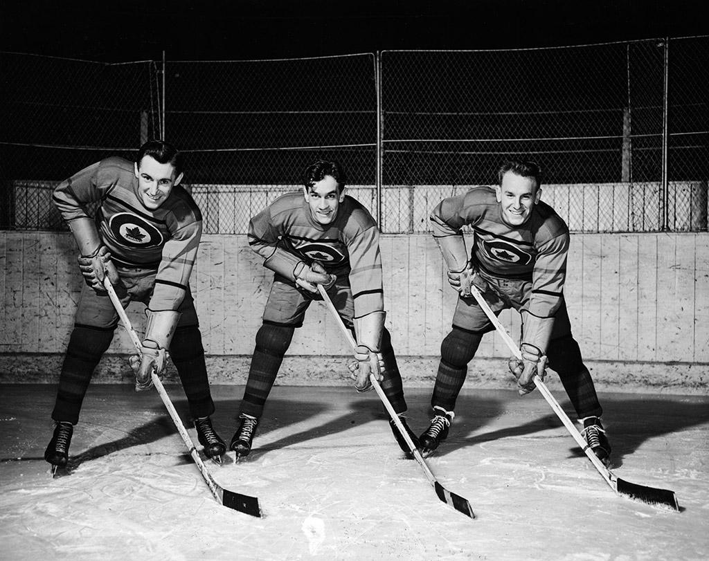 Drei Eishockey-Spieler schauen lachend in die Kamera.