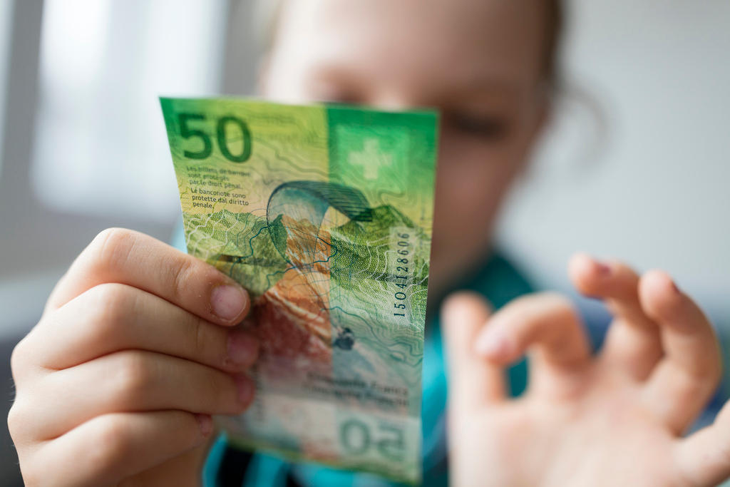 A child holds a 50 franc note