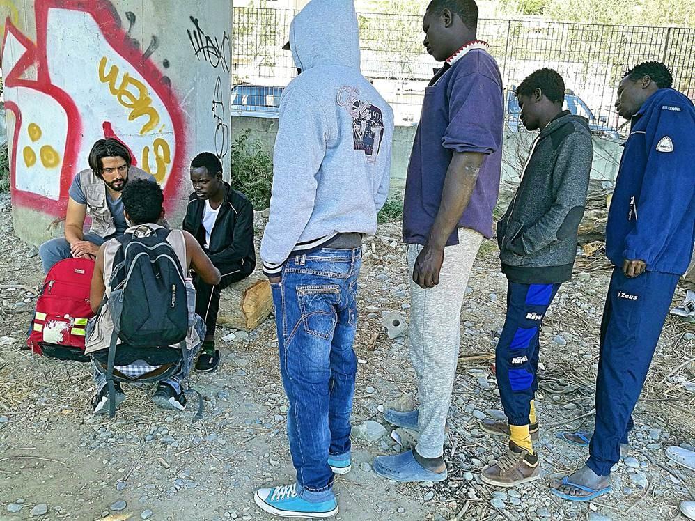 Giovani profughi sotto un viadotto, in coda per parlare con un operatore di INTERSOS a Ventimiglia.