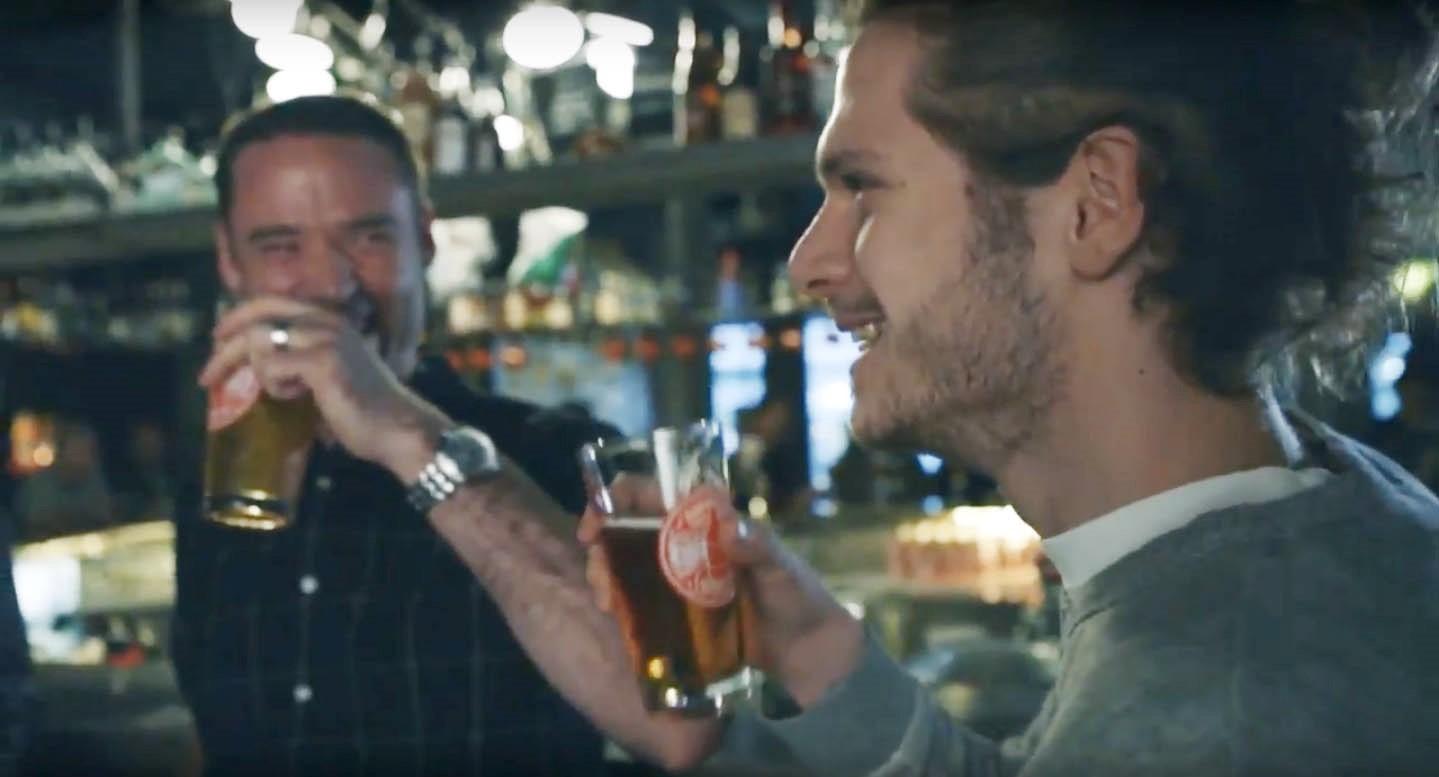Two men are drinking beer in a bar