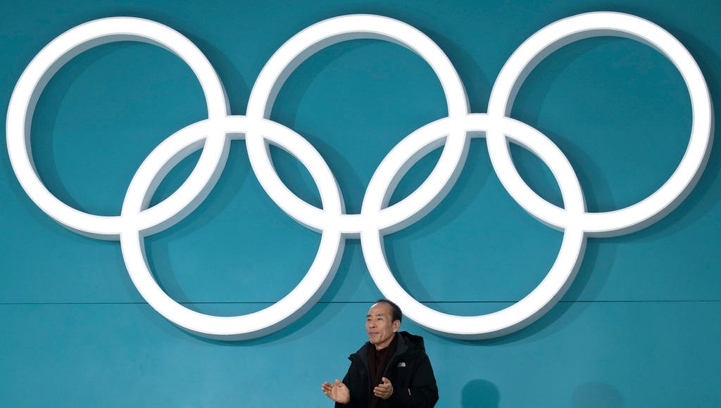 A man watches a game beneath the Olympic logo at this year s Winter Olympics in South Korea.