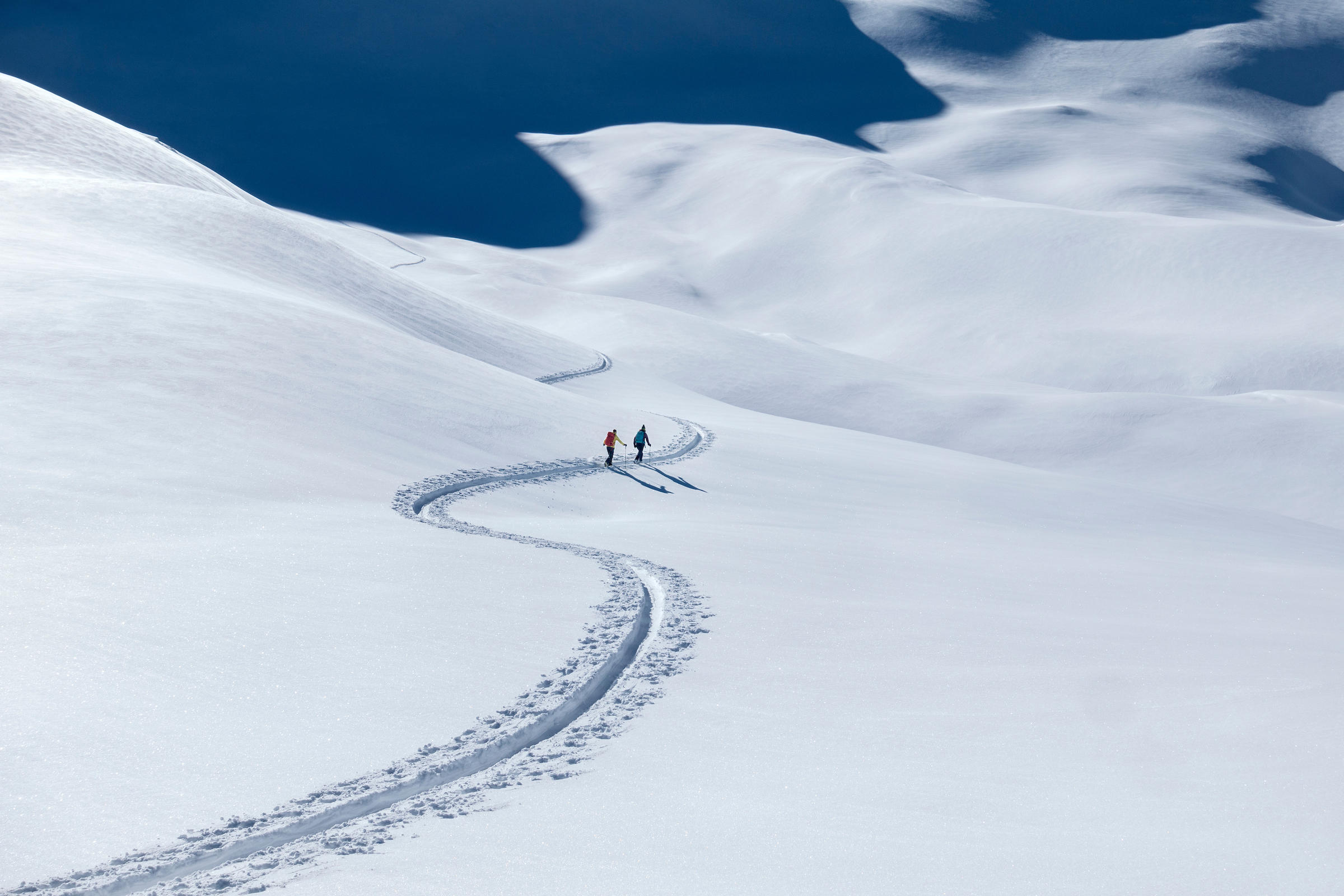 Skiers make tracks walking uphill