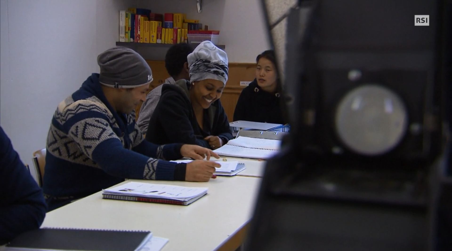 Immagine di quattro migranti, sui banchi con i loro quaderni a un corso di lingua